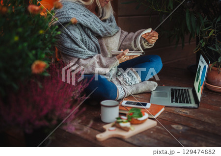 Elderly woman having dinner while working from homeoffice. 129474882
