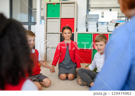 School kids and teacher sitting in circle on floor, talking about emotions. Morning Circle. 129474962