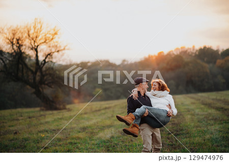 Senior husband carrying his wife in arms, romantic moment. 129474976