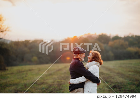 Senior couple embracing in autumn sunset light. Senior couple embracing in autumn sunset light. 129474994