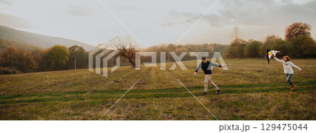Senior couple flying a kite during warm autumn evening. 129475044