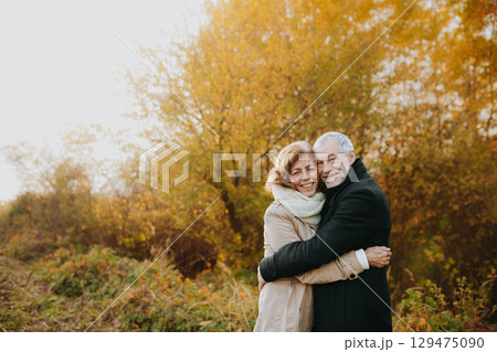Romantic walk through fall forest by senior couple. 129475090