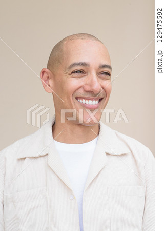 Bald Latin man face in casual shirt against beige background Bald Latin man face in casual shirt against beige background 129475592