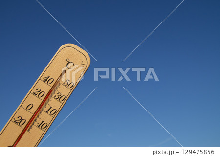摂氏37度を示す板付き温度計と快晴の青空 129475856