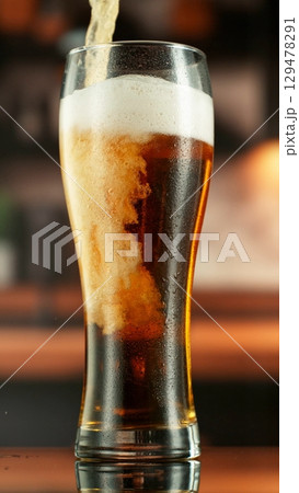 Pouring Beer into Large Glass with Blur Interior Background. Detail of Pint of Beer, Beverages Background. Vertical Aspect Ratio. Pouring Beer into Large Glass with Blur Interior Background. Detail of Pint of Beer, Beverages Background. Vertical Aspect Ratio. 129478291