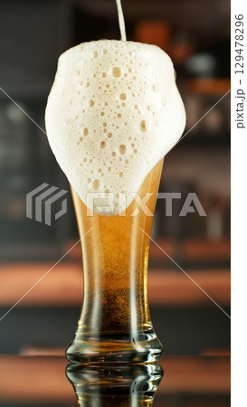 Pouring Beer into Large Glass with Blur Interior Background. Detail of Pint of Beer, Beverages Background. Vertical Aspect Ratio. 129478296