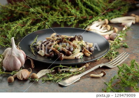 Fried shimeji mushrooms with thyme and garlic on a black plate. Fried shimeji mushrooms with thyme and garlic on a black plate. 129479009