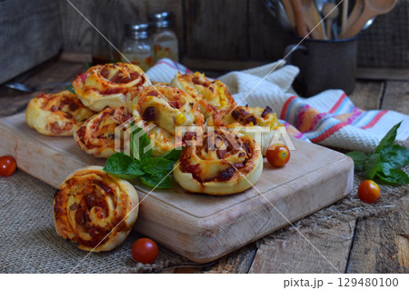 Buns of yeast dough with tomatoes, ham and cheese on a wooden background. Mini pizzas. homemade baking 129480100