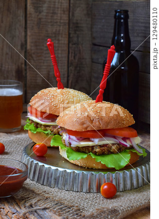 Veggie burgers with chop of eggplant, lettuce, pickled onions, tomato on a brown wooden background. Vegetarian lunch or dinner idea. Healthy food. 129480110