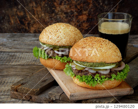veggie burgers with a chop of black beans, lettuce, pickled onions, cucumber on a brown wooden background. 129480120