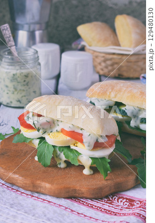 Sandwich from bun panini, cheese sauce, eggs, arugula, tomato and cucumber. Breakfast or snack. Vegetarian food. Healthy diet concept. Rustic photo. Copy space Sandwich from bun panini, cheese sauce, eggs, arugula, tomato and cucumber. Breakfast or snack. Vegetarian food. Healthy diet concept. Rustic photo. Copy space 129480130