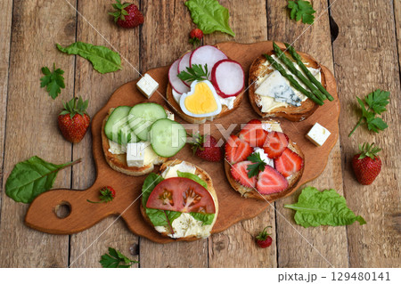 Set of healthy whole wheat bread sandwiches with fuits, vegetables, cheese and leafy green herbs on picnic wooden table. Ciabatta sandwich bar or buffet. Top view. Making lunch time snacks concept 129480141