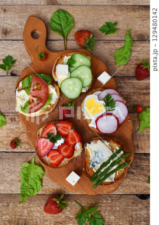 Set of healthy whole wheat bread sandwiches with fuits, vegetables, cheese and leafy green herbs on picnic wooden table. Ciabatta sandwich bar. Top view. Lunch time snacks concept. Vegetarian food Set of healthy whole wheat bread sandwiches with fuits, vegetables, cheese and leafy green herbs on picnic wooden table. Ciabatta sandwich bar. Top view. Lunch time snacks concept. Vegetarian food 129480142