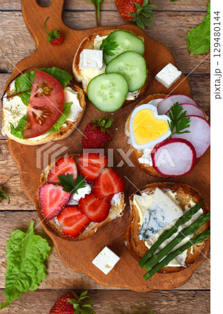 Set of healthy whole wheat bread sandwiches with fuits, vegetables, cheese and leafy green herbs on picnic wooden table. Ciabatta sandwich bar or buffet. Top view. Making lunch time snacks concept 129480144