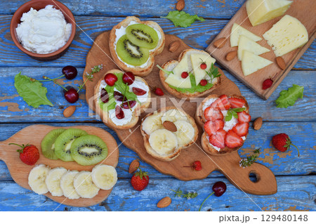 Set of healthy whole wheat bread sandwiches with fuits, vegetables, cheese and leafy green herbs on picnic wooden table. Ciabatta sandwich bar. Top view. Lunch time snacks concept. Vegetarian food 129480148