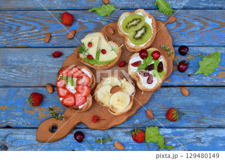 Set of assorted healthy wholewheat bread sandwiches with fruit, cheese and leafy green herbs on picnic wooden table. Ciabatta sandwich bar or buffet. Top view. Making lunch time snacks concept. 129480149