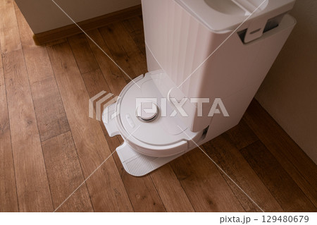 Robot vacuum in action first removes debris then follows with wet mopping to leave the floor clean and shiny. 129480679