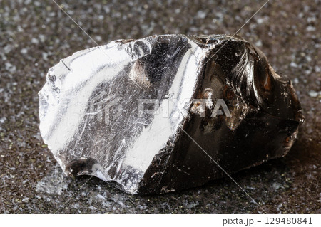 sample of raw obsidian mineral on black 129480841