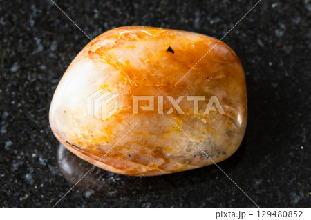 sample of tumbled orange quartz mineral on black 129480852