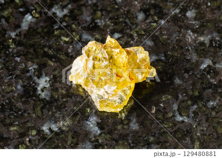 sample of raw sinhalite mineral on black granite 129480881
