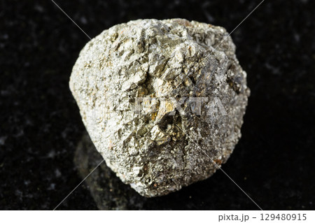 sample of unworked pyrite rock on black granite 129480915
