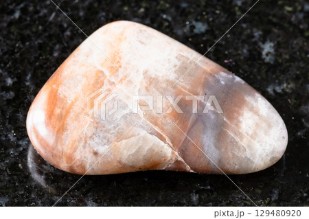 sample of tumbled nepheline rock on black granite 129480920