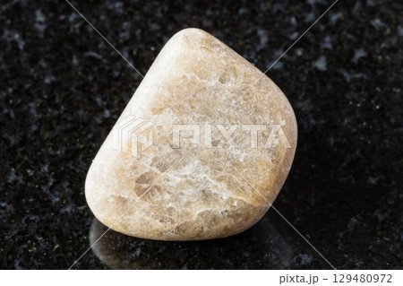 sample of polished cryolite rock on black granite 129480972