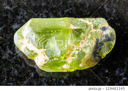 sample of raw peridod crystal on black granite 129481145