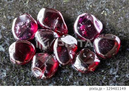 many polished rhodolite crystals on black granite many polished rhodolite crystals on black granite 129481149