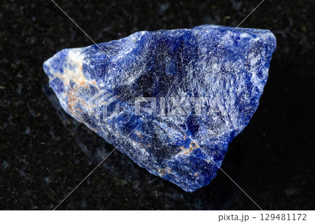 sample of raw sodalite rock on black granite 129481172