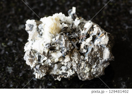 sample of rough arsenopyrite rock on black granite 129481402