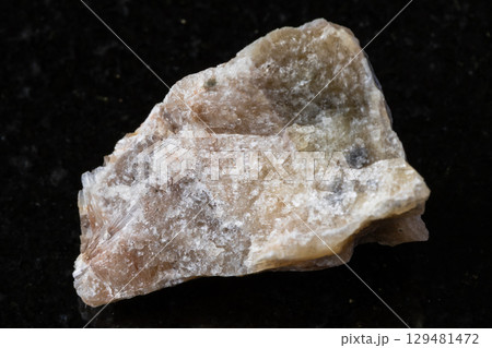 sample of raw cancrinite rock on black granite 129481472