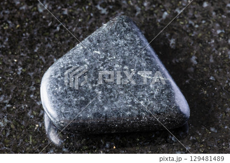 sample of tumbled dolerite rock on black granite 129481489