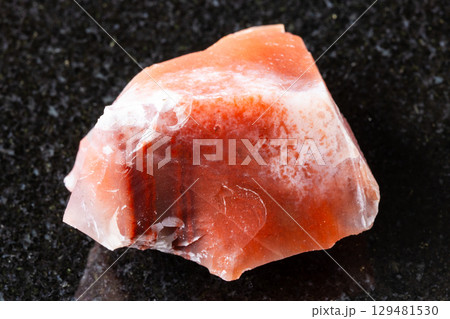 sample of raw carnelian mineral on black granite 129481530
