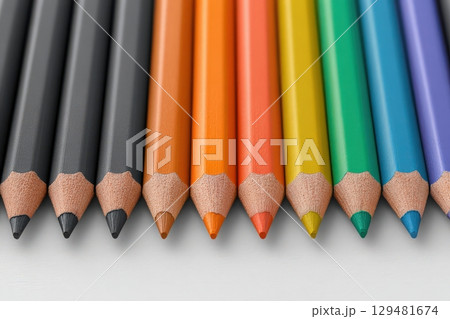 A variety of colored pencils are carefully aligned in a row, showcasing vibrant colors from black to green. The sharpened tips glisten under soft light, inviting creativity for artistic projects. 129481674