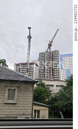 Construction site with high-rise buildings and tower cranes against a cloudy sky. Concept of urban development, growth and modern architecture 129481752
