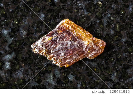 sample of rough rutile mineral on black granite 129481916