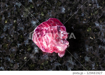 sample of raw red spinel crystal on black granite 129481927