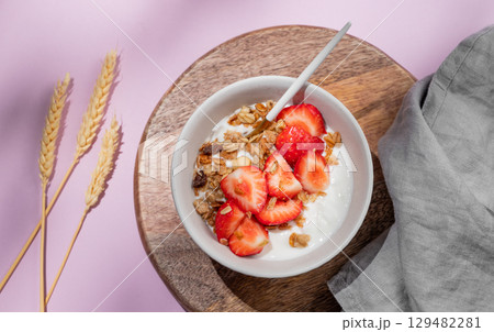 Granola or muesli with natural greek yogurt, strawberry in a bowl on a wooden board  129482281