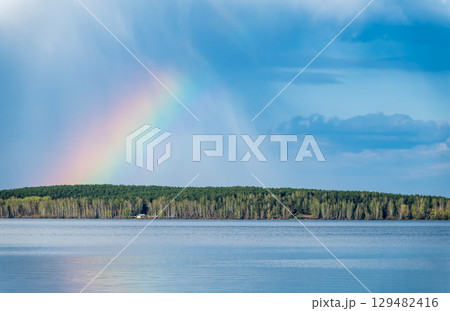 Rainbow over Blue lake with cloudy sky 129482416
