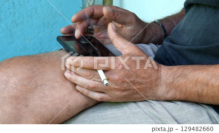 Asian man hands with cigarette and phone tapping by finger 129482660