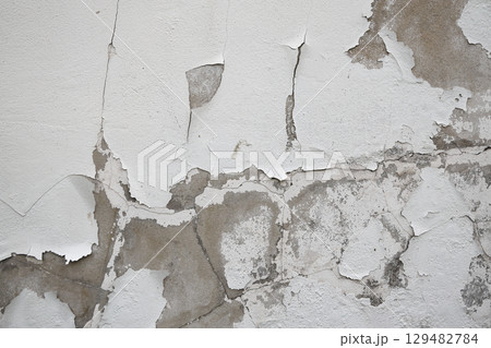 Close up of old stucco cracks on the wall, Old cracked paint on the concrete wall, Weathered paint cracks on plaster. Cracked wall background. 129482784