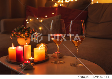 Cozy evening scene with candles, wine glasses and warm lighting. 129482844