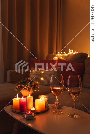 Cozy evening scene with candles, wine glasses and warm lighting. 129482845