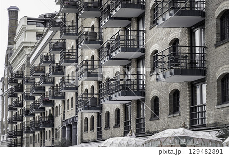 a multi-story building characterized by its brick facade, arched windows and numerous balconies with dark-colored railings. 129482891