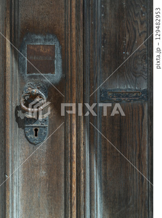 Aged wooden door with Ornamental keyhole and knocker, Antique wooden gate of Holy trinity church. 129482953