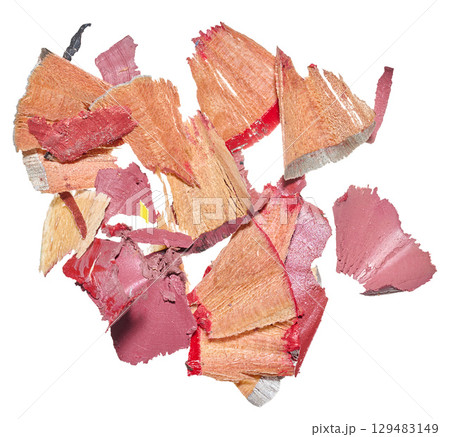 A pile of different sized shavings from sharpened colored pencils. The wooden parts and bright red and pink remains of the leads are visible. 129483149