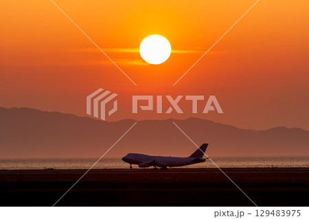 夕日を背景に着陸するジャンボジェット機 129483975