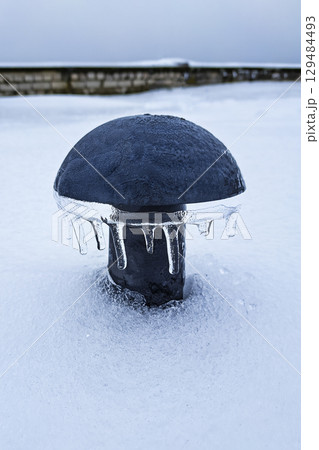 Black plastic air vent, mushroom shaped air vent in winter in snow and icicles on the roof of a 129484493