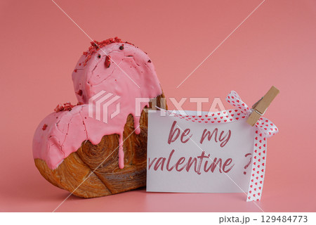 BE MY VALENTINE message on paper note greeting card Delicious fresh croissant topped with colorful flavor Ganache. Creation unique heart shape bakery. Puff pastry holiday love gift present idea 129484773
